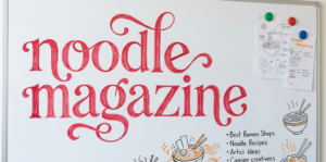 Noodle Magazine written in beautiful red lettering on a whiteboard